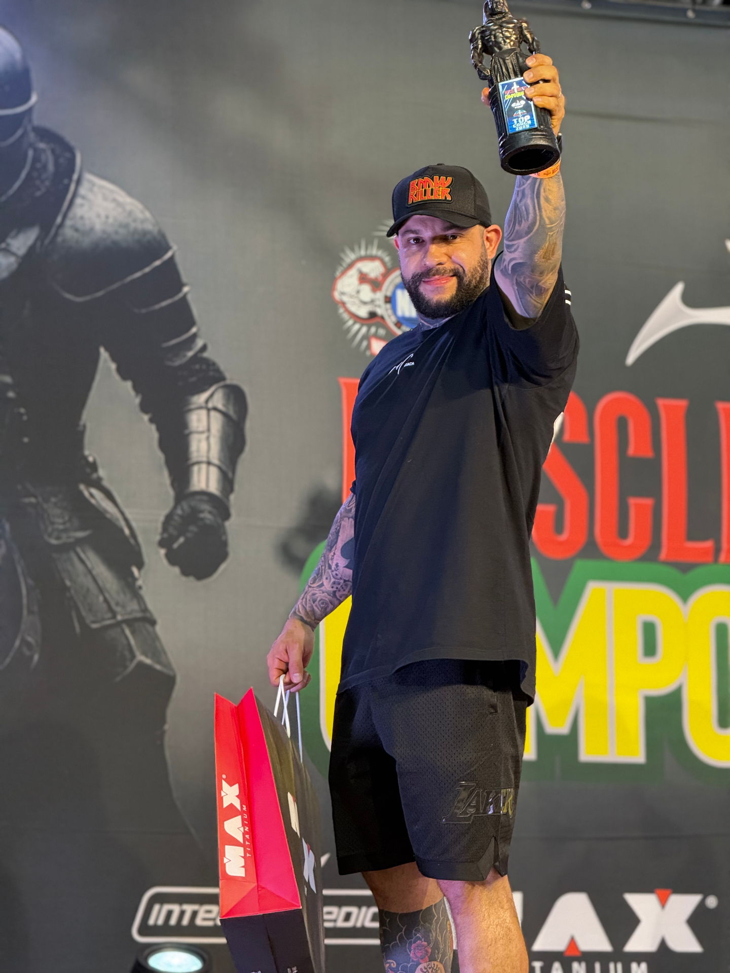 Wendel Castro erguendo o troféu de Top Coach em campeonato de fisiculturismo